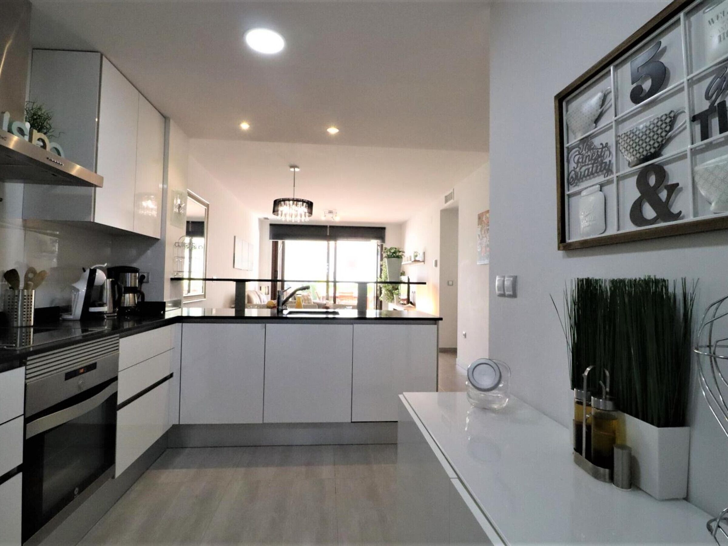 A modern kitchen with white cabinets, a black countertop, and a built-in oven.