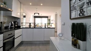 A modern kitchen with white cabinets, a black countertop, and a built-in oven. - Family apartment 3 bedrooms near beach (San Juan de los Terreros)