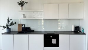 Eine moderne Küche mit weißen Schränken, einer schwarzen Arbeitsplatte und Holzboden.