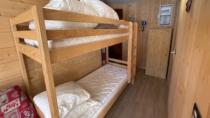 A bunk bed in a wooden room with a door and a light switch on the wall. - Charming renovated studio with balcony in Lioran (Le Lioran)