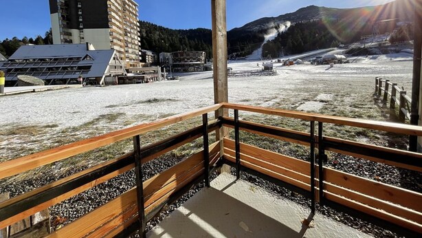 A balcony with a view of a snowy landscape, a building, and a mountain in the background. - Charming renovated studio with balcony in Lioran (Le Lioran)