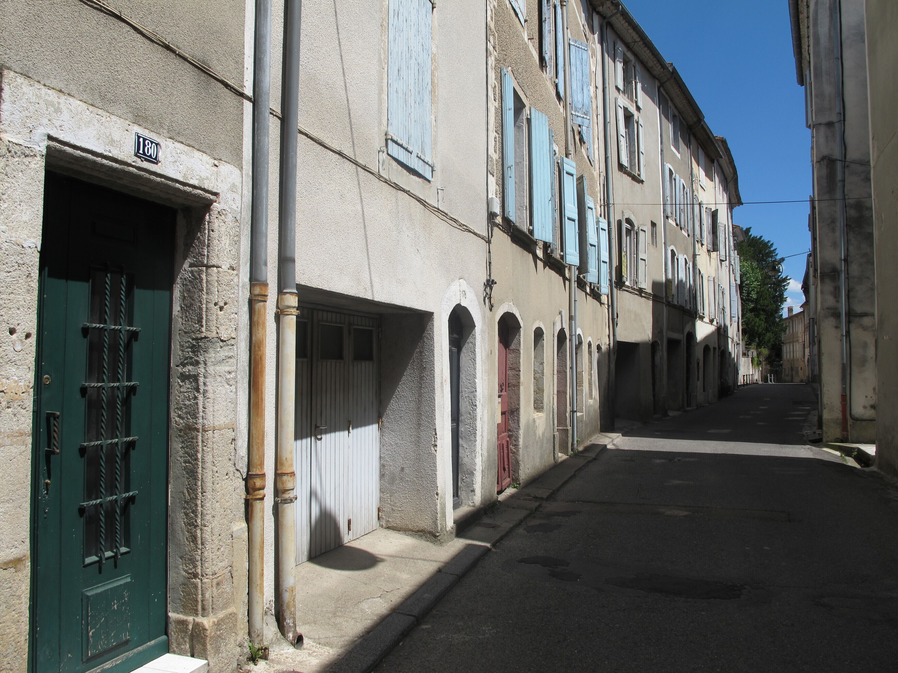 Una calle estrecha flanqueada por edificios con arcos y persianas tradicionales.