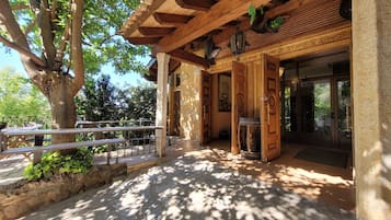 A wooden building with a covered entrance, stone steps, and a bench.