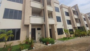 A multi-story residential building with balconies, a paved entrance area, and potted plants. - AAMIQ SPACE (Abuja)