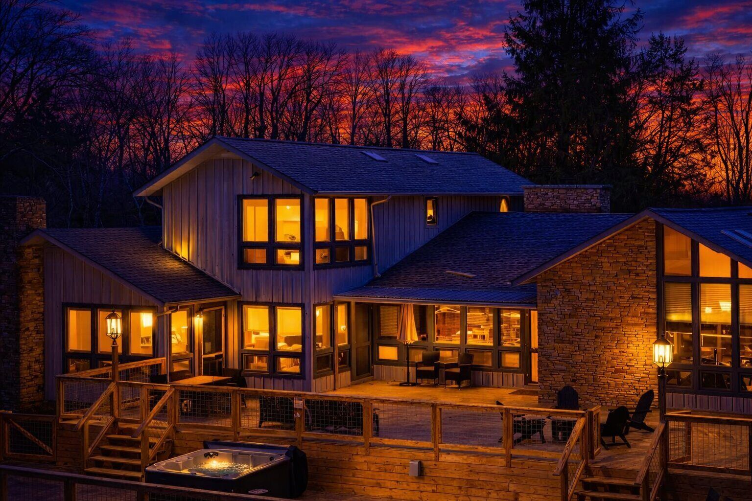 Een houten chalet met twee verdiepingen, grote ramen, een terras en een hottub.