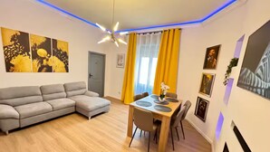 Ein modernes Wohnzimmer mit einer grauen Eckcouch, einem Holzespeisetisch mit Stühlen und einem Deckenventilator.