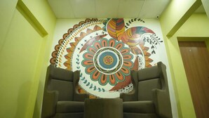 Un hall d’entrée avec deux fauteuils et une fresque murale aux couleurs vives.