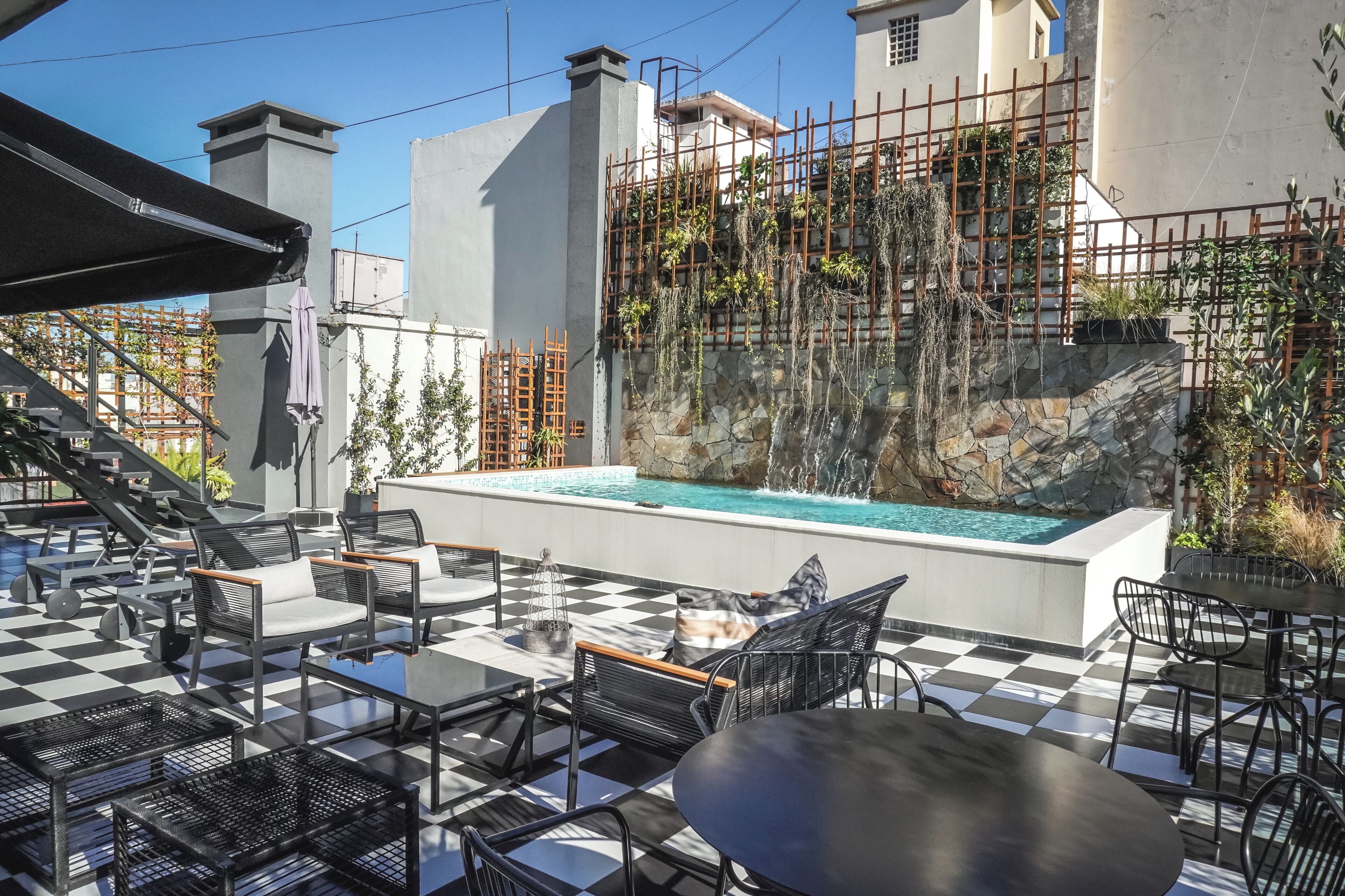 Un espace extérieur aménagé avec des sièges, une piscine, un sol à carreaux et une vue sur un bâtiment en cours de rénovation, avec des échafaudages.