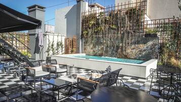 Un espace extérieur aménagé avec des sièges, une piscine, un sol à carreaux et une vue sur un bâtiment en cours de rénovation, avec des échafaudages.