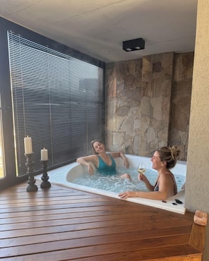 A spa room with a stone wall, a wooden floor, and a window with blinds. - Aira Apart Hotel Boutique (Buenos Aires)