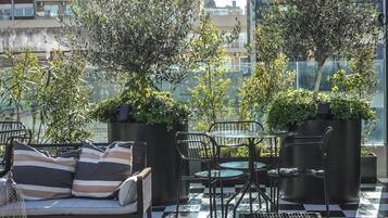 Une terrasse sur le toit, avec des espaces de détente en plein air, des plantes en pot et une vue sur le paysage urbain.