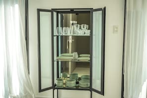 Een kamer met een spiegelkast vol glazen, borden en kommen.