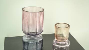 Two glass vases with ribbed textures on a dark surface.