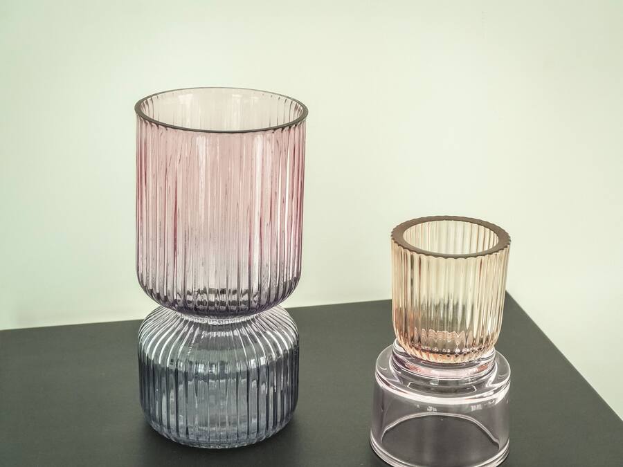 Two glass vases with ribbed textures on a dark surface.