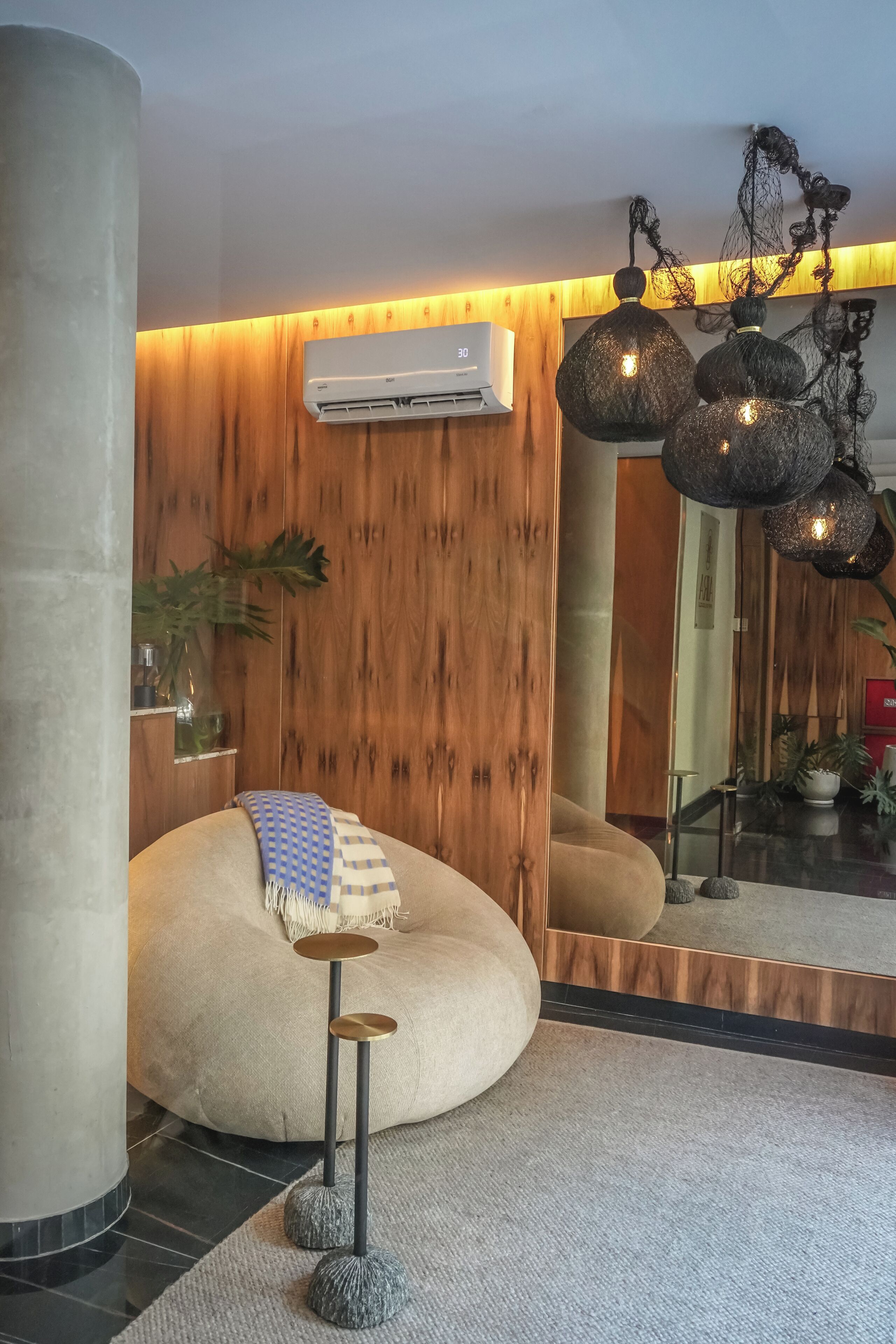 A modern interior with a round bean bag chair, a small round table, and a wall-mounted air conditioner.