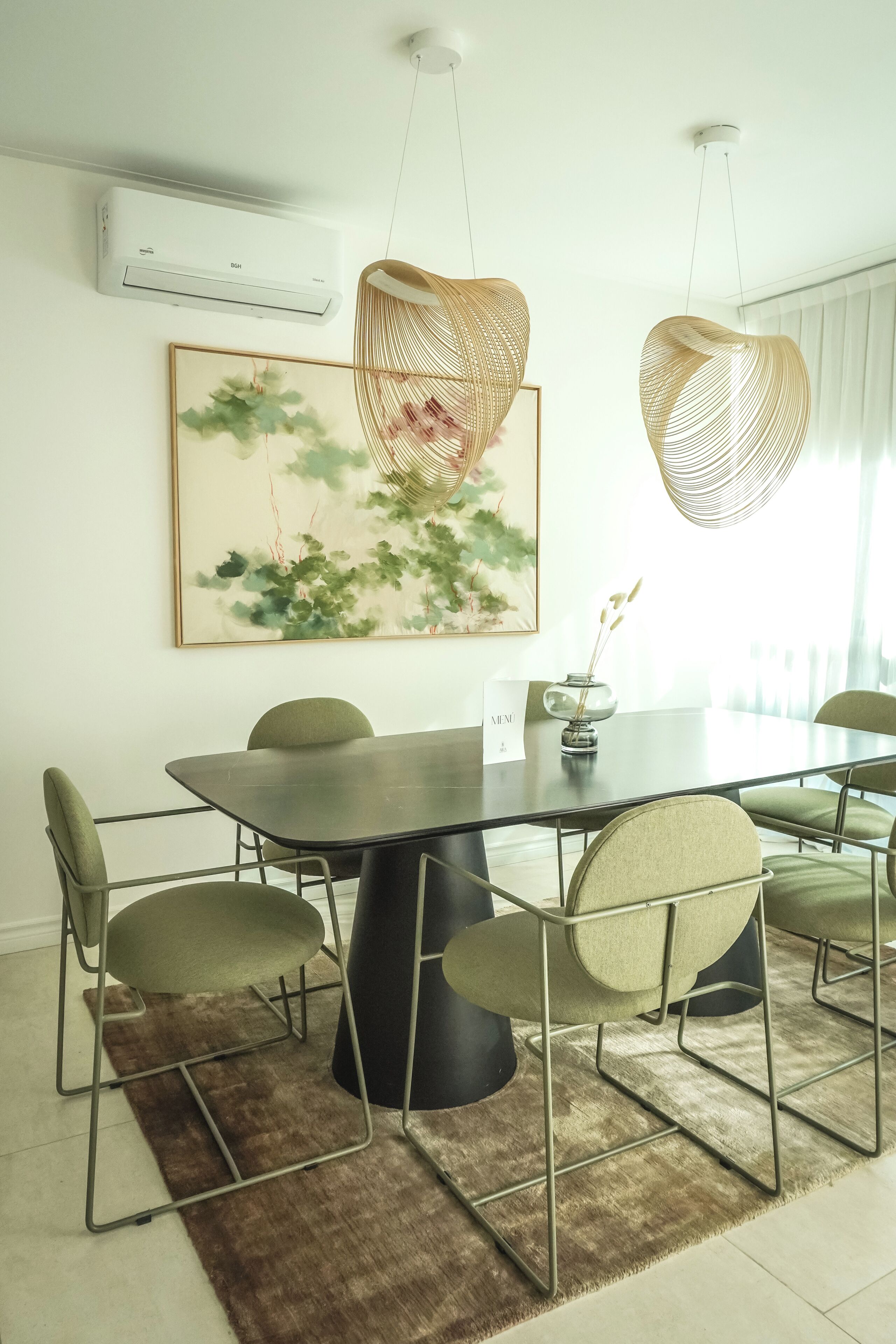 Un coin repas avec une table ronde, six chaises, un tapis marron, un climatiseur fixé au mur et un tableau encadré.