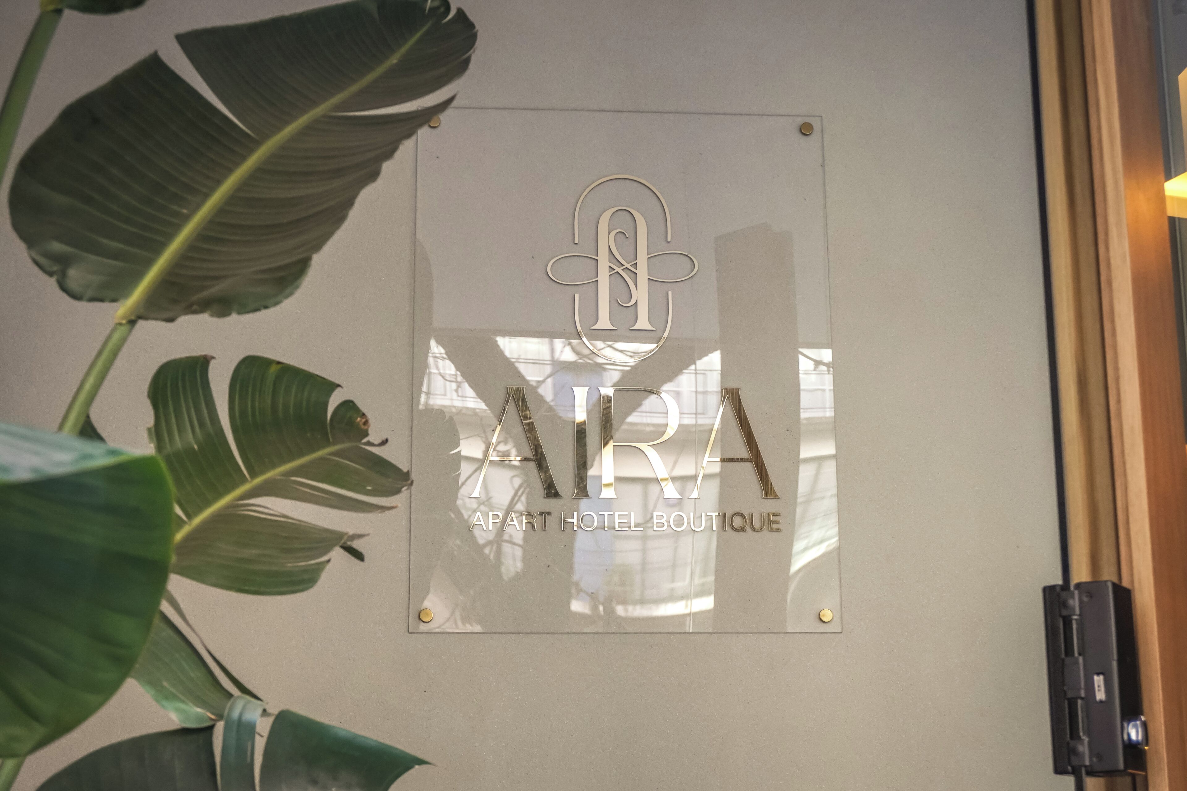A clear glass sign with the text 'APART HOTEL BOUTIQUE' and a stylized 'A' logo.