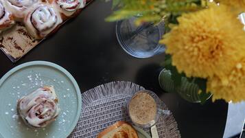 A table with food items, a vase with yellow flowers, and a metal chair.