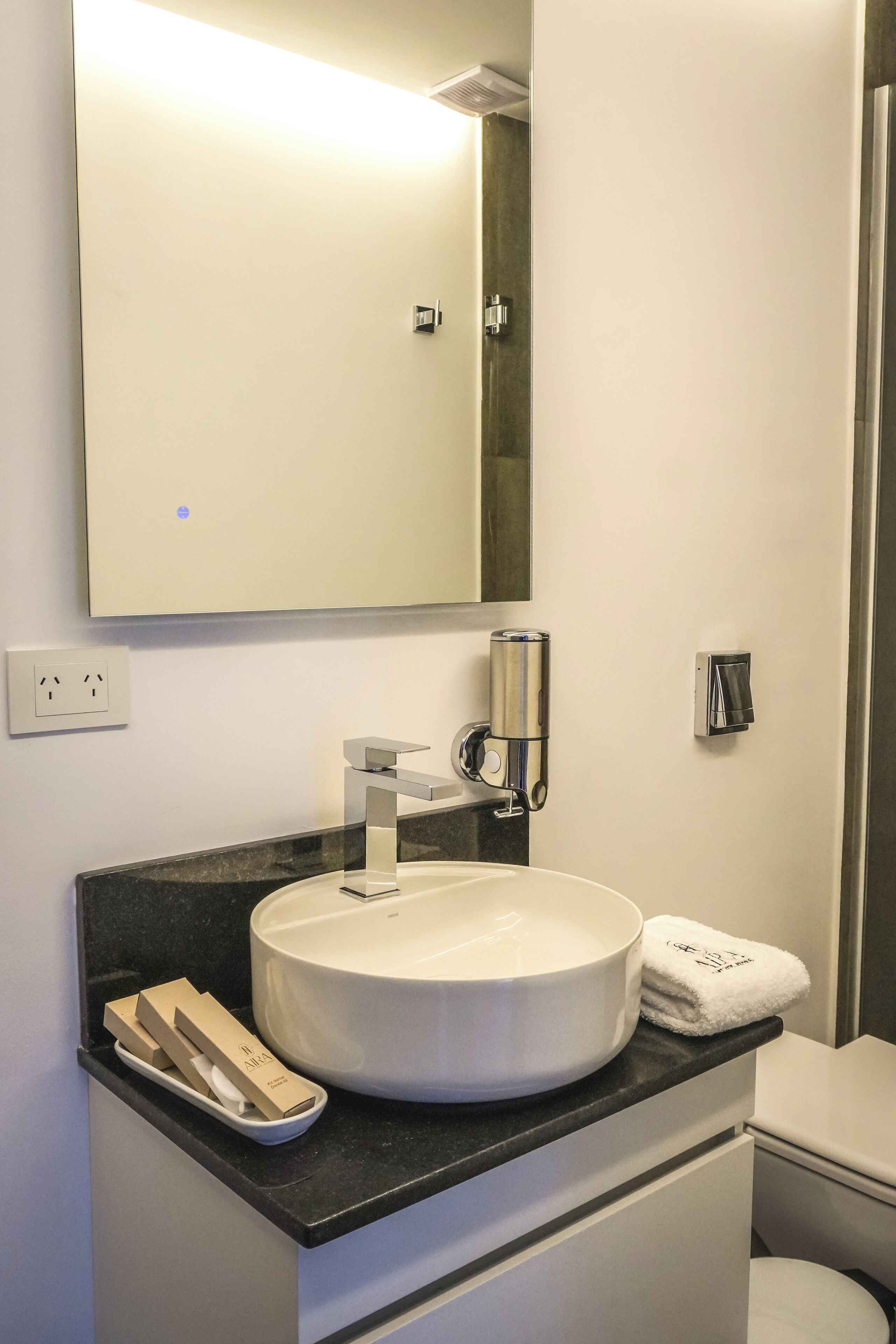 Ein modernes Badezimmer mit einem runden Waschbecken, einem Spiegel und einem Handtuchhalter.