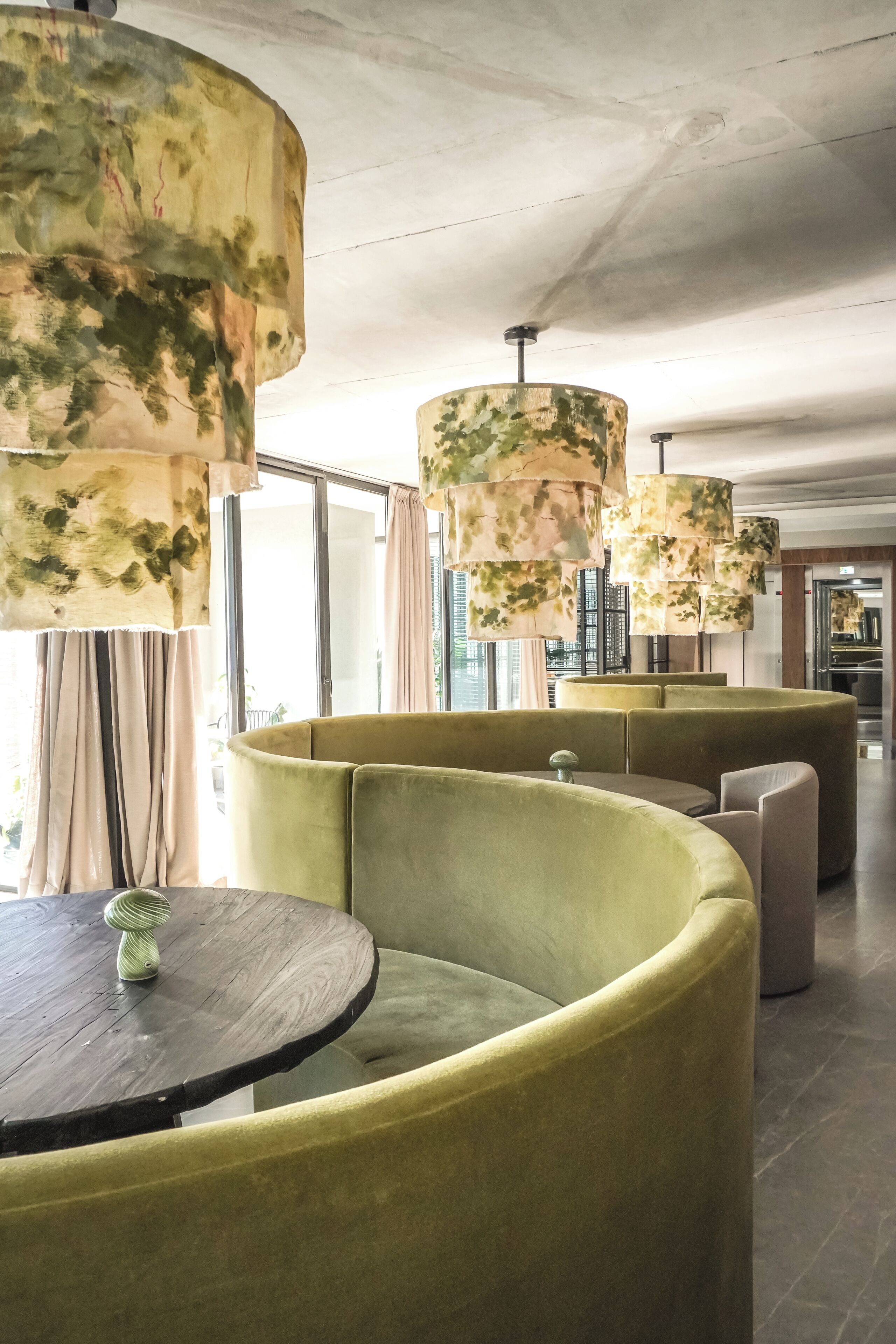 A modern interior with round tables and green upholstered seating.