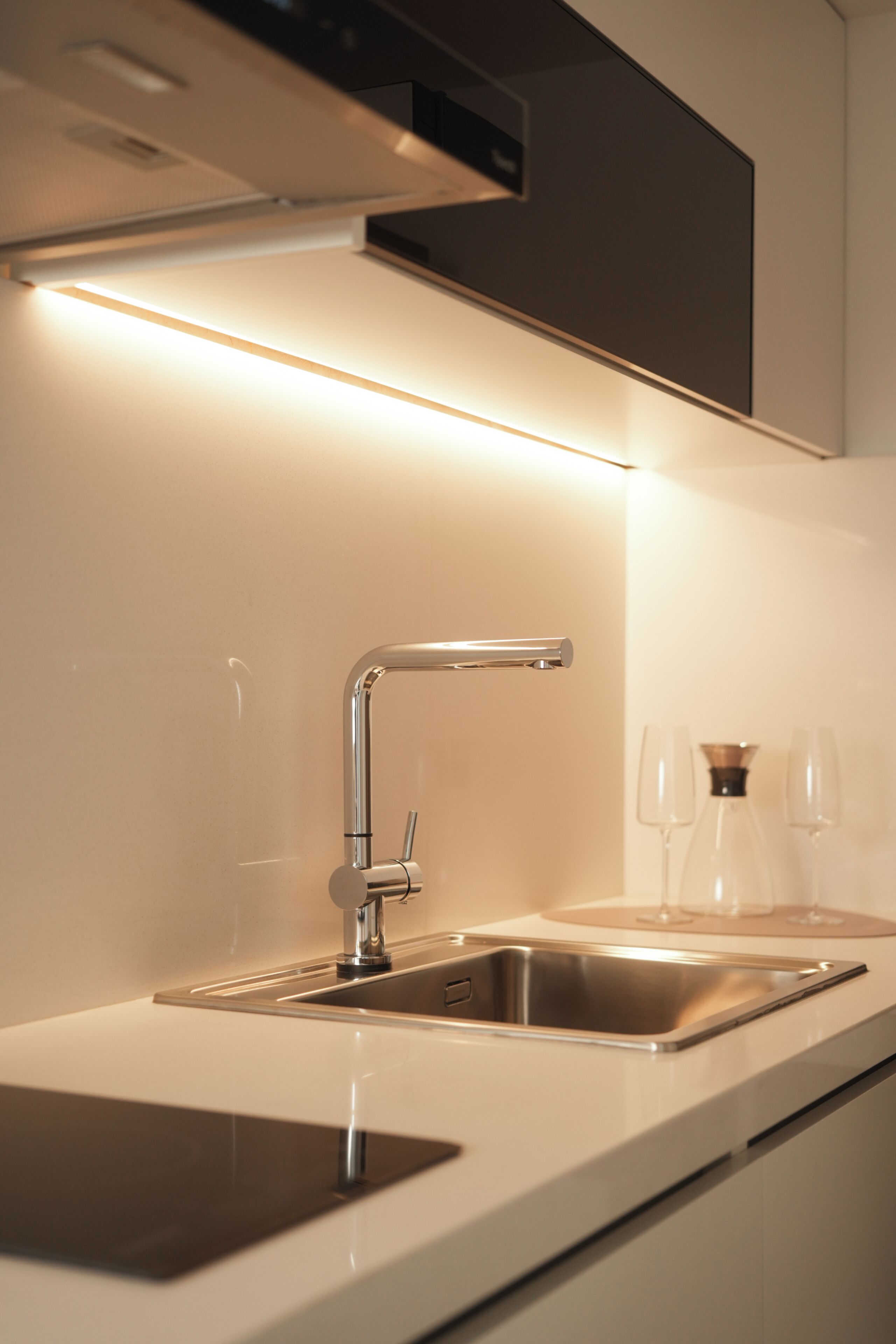 Una cocina moderna con un lavamanos de acero inoxidable, un grifo y un horno empotrado.