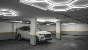 A parking garage with a white SUV parked under a ceiling with hexagonal light fixtures.