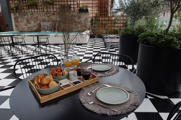 Une table à manger dressée avec des aliments pour le petit-déjeuner, un plateau et des verres de jus d’orange.