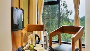 A room with a dining table, chairs, a refrigerator, and a window with curtains. - HOTEL SAYBA INTERNATIONAL (Pune)