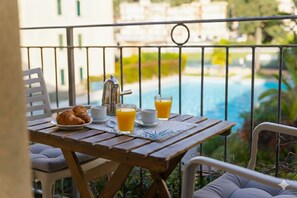 A wooden table with breakfast items and a view of a swimming pool. - Studio Cala di Sole (Imperia)