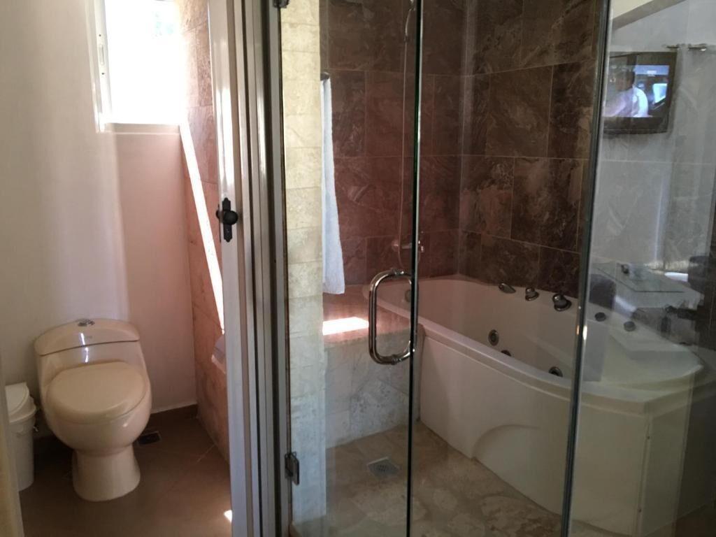 A bathroom with a toilet, a glass-enclosed shower, and a bathtub.