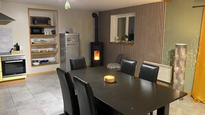 A modern kitchen with a dining area, featuring a built-in oven, microwave, and a wood-burning stove. - Cozy vacation rental for 6 people, with a garden in Normandy, near the D-Day beaches (La Luzerne Manche)