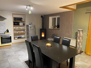 A modern kitchen with a dining area, featuring a built-in oven, microwave, and a wood-burning stove. - Cozy vacation rental for 6 people, with a garden in Normandy, near the D-Day beaches (La Luzerne Manche)