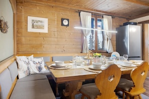 Un intérieur en bois comprenant une table à manger pour quatre personnes, un canapé et un réfrigérateur.
