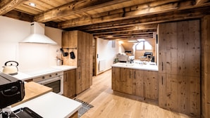 A kitchen with wooden beams, white countertops, and a view into a living area. - Holiday Home “L'alpin” with Mountain View (Les Déserts)