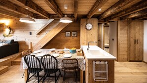 A wooden interior with a dining area, a clock, and a kitchen. - Holiday Home “L'alpin” with Mountain View (Les Déserts)
