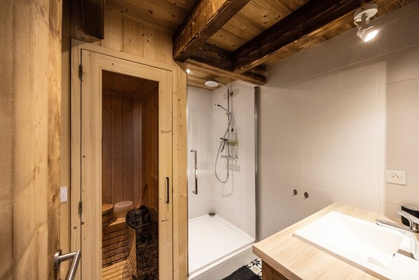 Ein Holzinnenraum mit Dusche, Badewanne und Waschbecken.