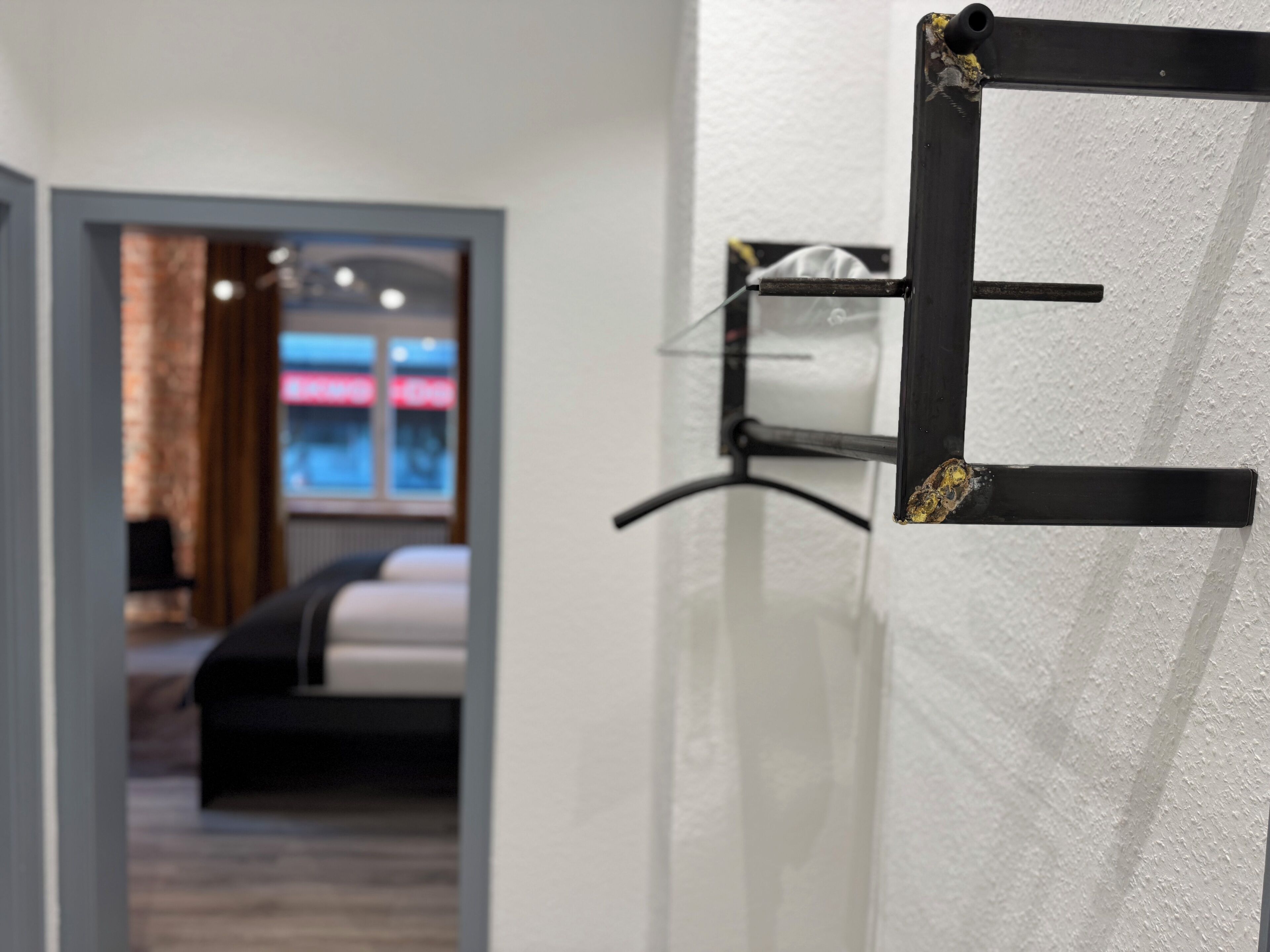Una camera d'albergo con un letto, uno scaffale a muro e una porta con maniglia.