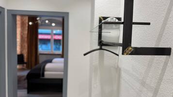 Una camera d'albergo con un letto, uno scaffale a muro e una porta con maniglia.