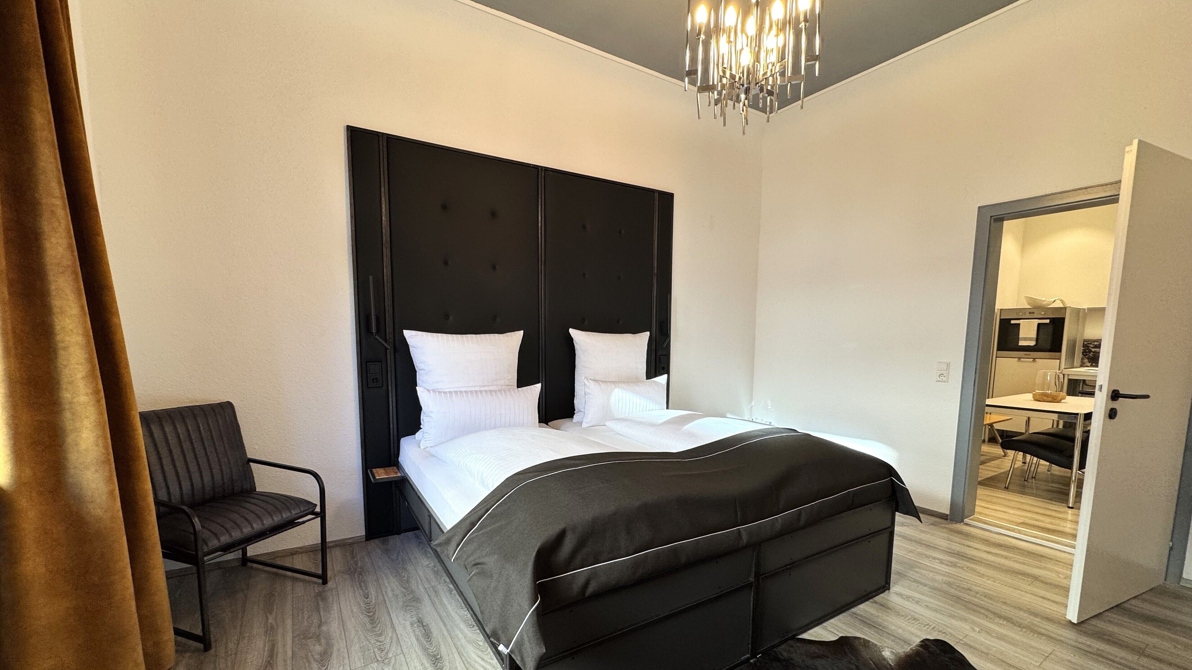 Une chambre d’hôtel moderne équipée d’un grand lit, d’une chaise et d’une kitchenette.