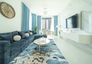 Ein modernes Wohnzimmer mit Sofa, Couchtisch und an der Wand montiertem Fernseher.