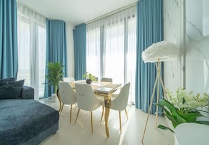 Ein modernes Wohnzimmer mit einer Couch, einem Esstisch, Stühlen und einer Stehlampe.