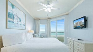 A bedroom with a large bed, a ceiling fan, a TV, a window with curtains, and a painting on the wall. - Stunning 3BR Beachfront Condo - Heated Pool - Orange Beach Enclave #405 (Orange Beach)