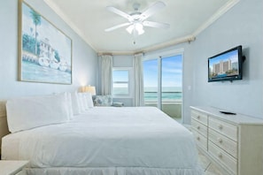 A bedroom with a large bed, a ceiling fan, a TV, a window with curtains, and a painting on the wall. - Stunning 3BR Beachfront Condo - Heated Pool - Orange Beach Enclave #405 (Orange Beach)