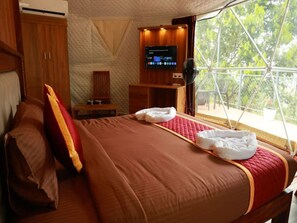 A bedroom with a large bed, a TV, and a window with a view of trees. - MunnarGlamp Munnar (Devikolam)