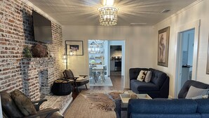 Ein Wohnzimmer mit Backsteinwand, Kamin, einer Chandelieber und einem Sofa.