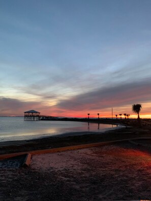 A beach with a pier extending into calm waters, a sandy shoreline, and a palm tree. - BOAT PARKING | Pet-Friendly | 2 Blocks to Downtown & Bay (Port Saint Joe)