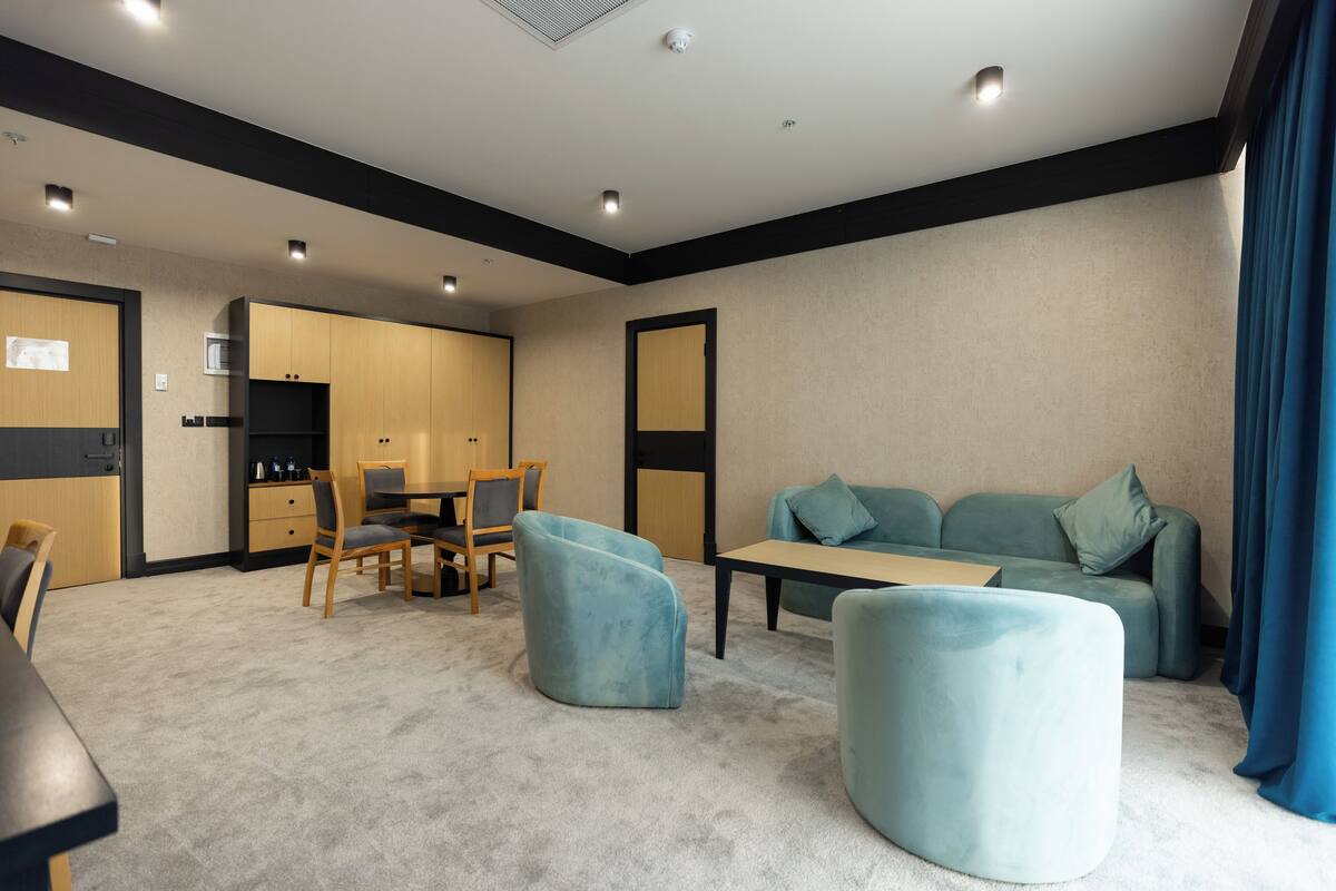 Una sala de estar moderna con sofá, reposapiés y comedor.
