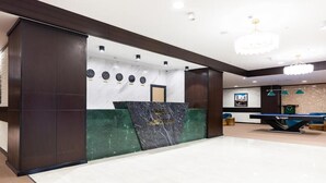 Un hall modern amb una taquilla d'atenció al client, rellotges i bitlles.