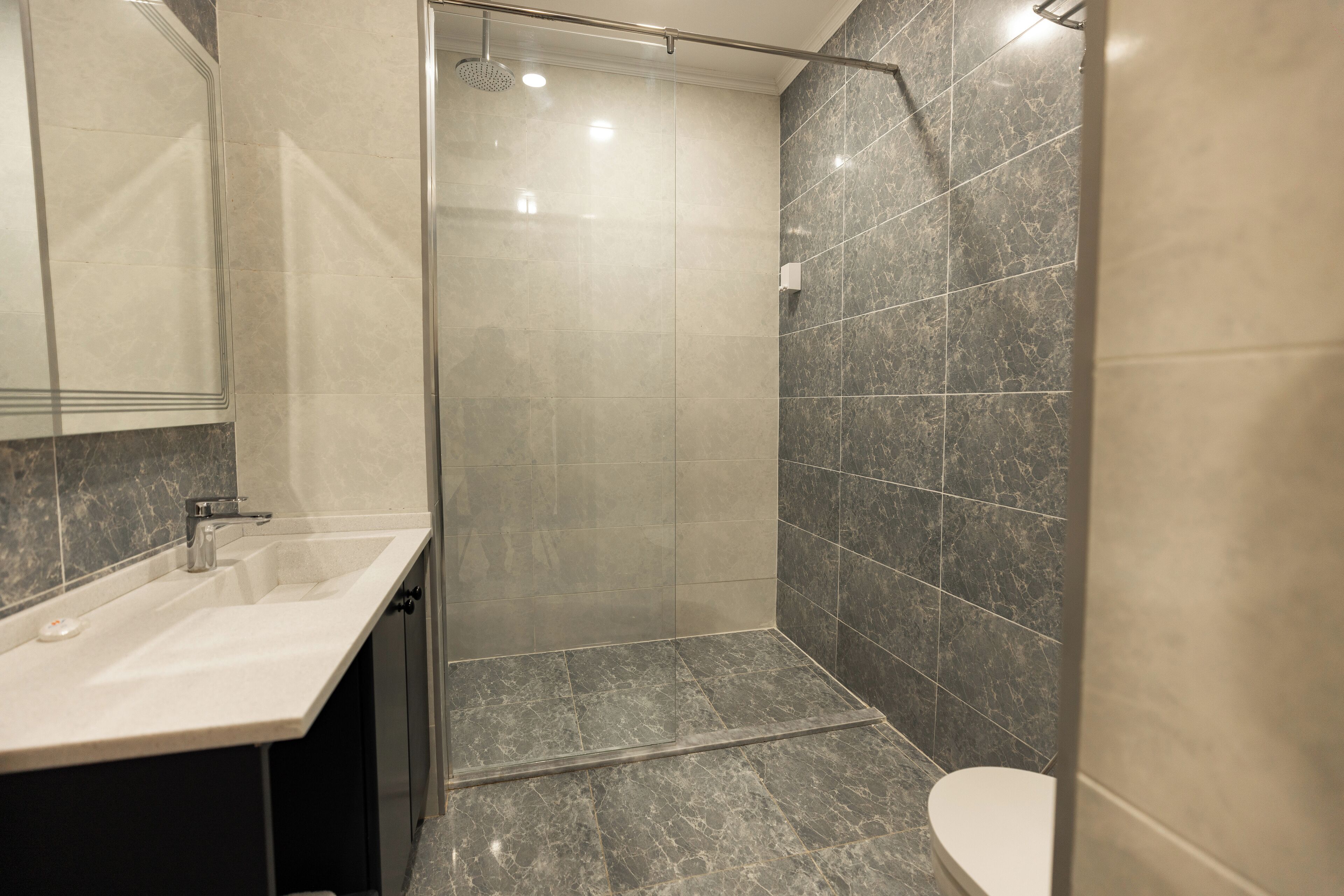 Un baño moderno con cabina de ducha de vidrio, lavamanos y inodoro.