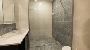 Un baño moderno con cabina de ducha de vidrio, lavamanos y inodoro.